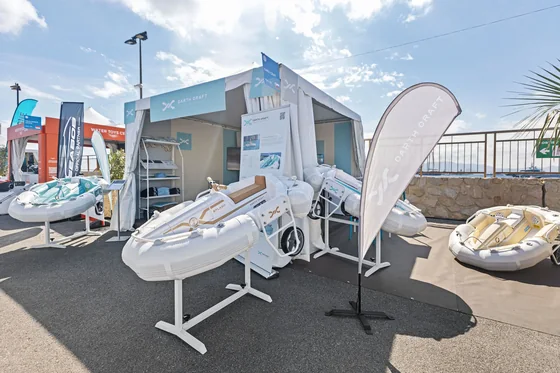 Zunanja postavitev na Cannes Yachting Festivalu: plovila na stojalih med beach flagi